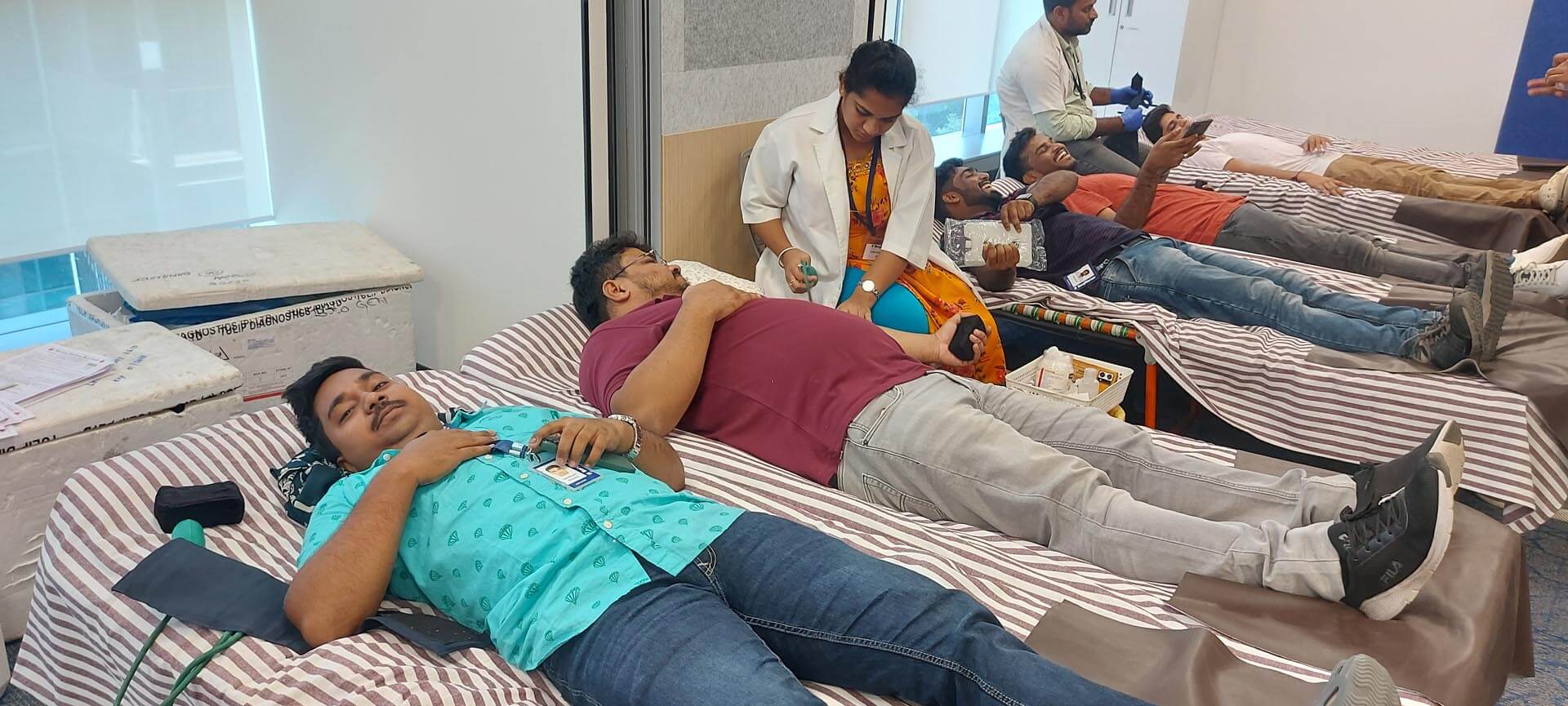 a group of people lying on beds donating blood