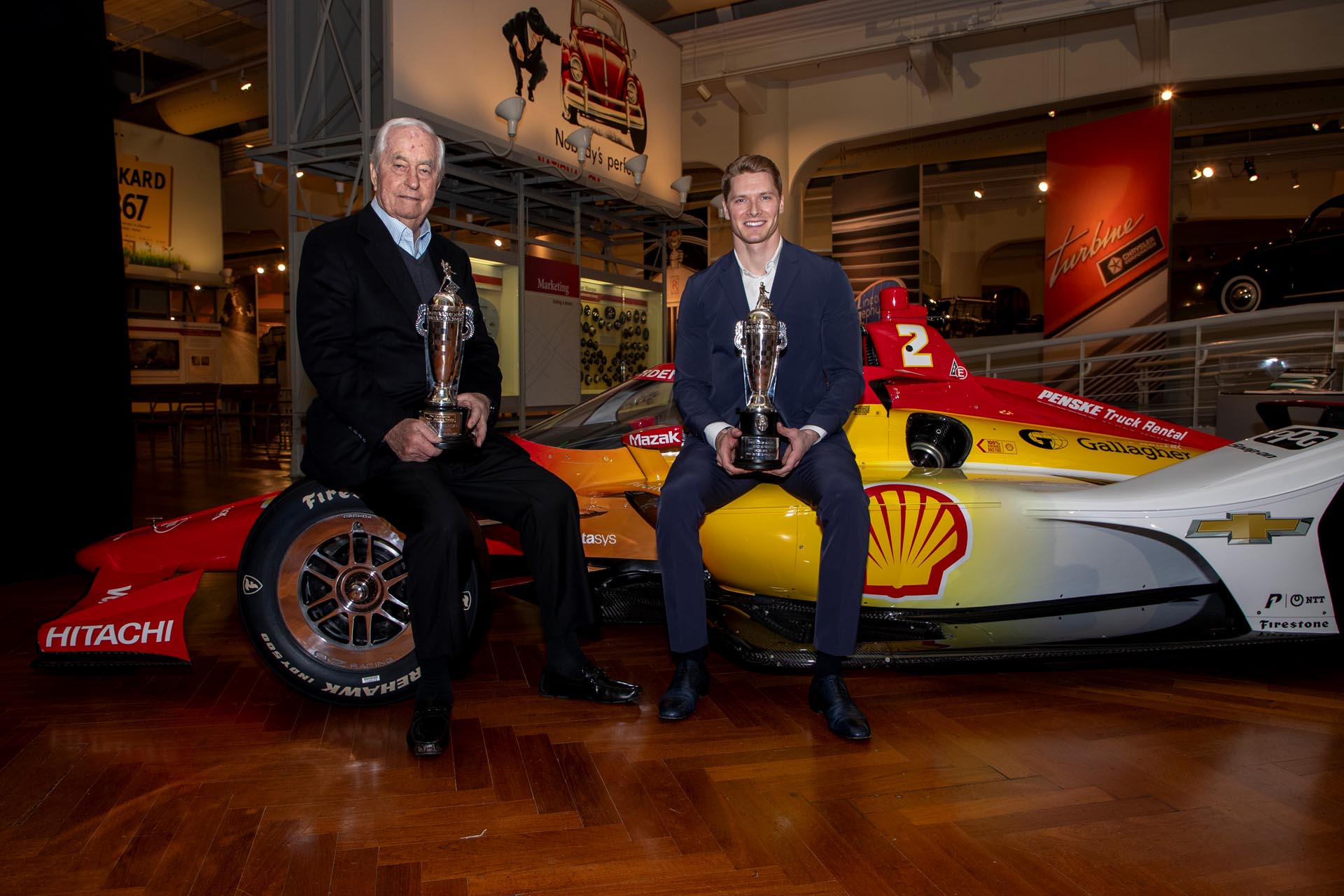 Roger Penske and Josef Newgarden sitting on a race car