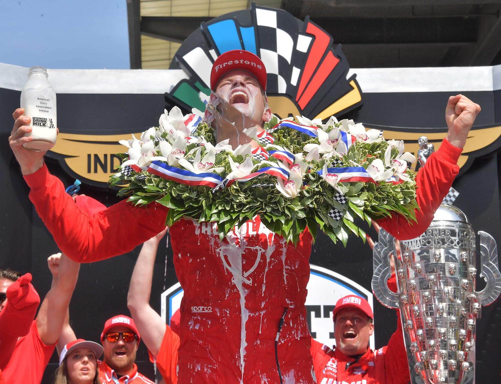 a person in red overalls with flowers and a trophy
