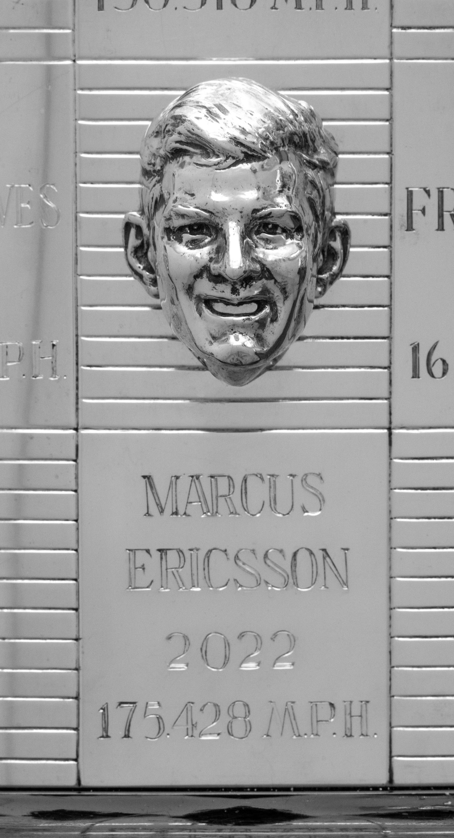 Sculpted head of smiling man above engraving on trophy
