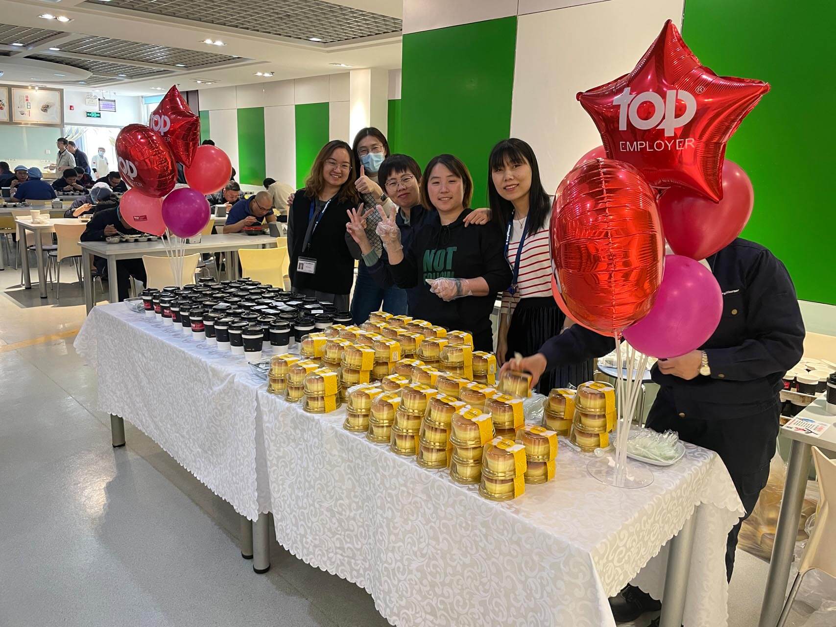 a group of people standing next to a table with food and balloons