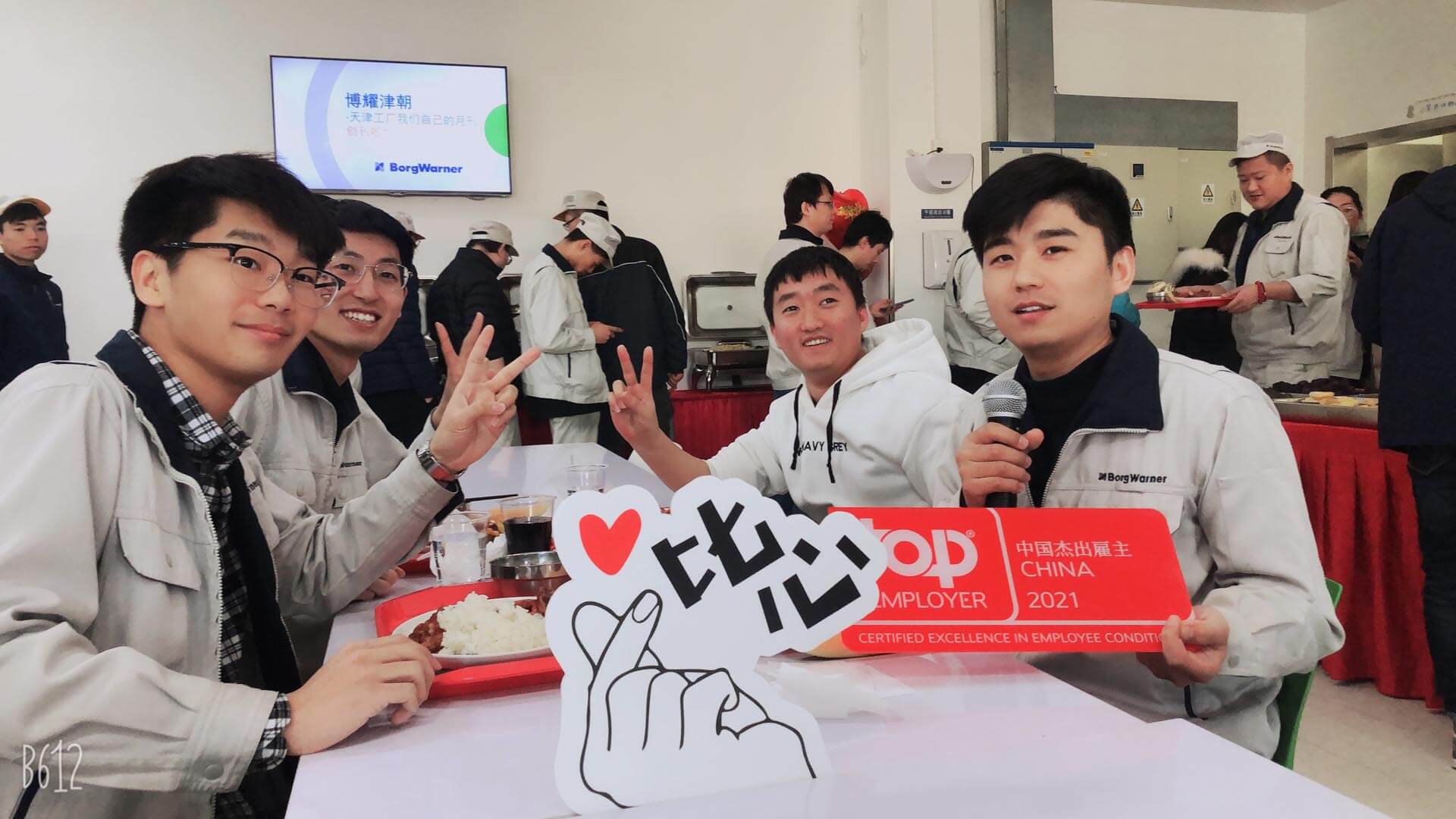Individuals at a corporate event with signage indicating "Top Employer China 2021